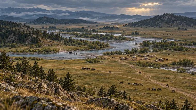 Editorial steppe landscape with a river crossing, routes, pasture and a small seasonal encampment seen from afar.